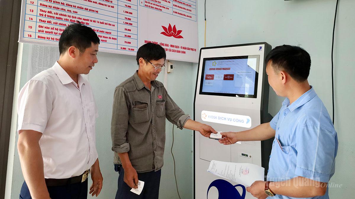 Cán bộ xã Hồ Thầu hướng dẫn người dân sử dụng máy lấy số tự động.